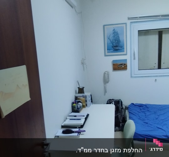 מזגן מותקן על קיר בחדר שינה עם מיטה ושולחן כתיבה